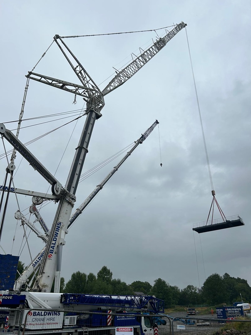 The main part of the bridge being lifted by a large crane