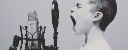 A young boy shouting into a microphone 