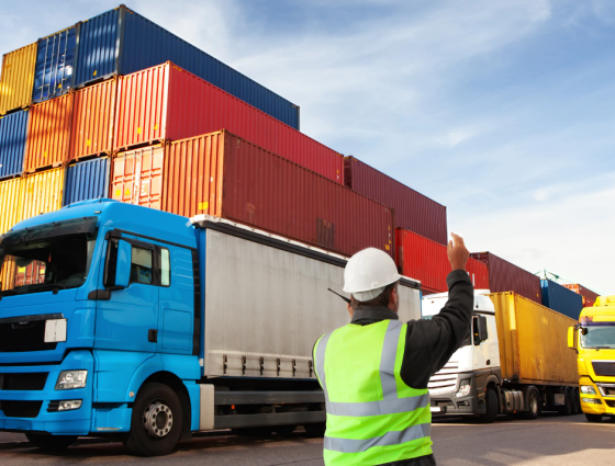 person waving a lorry through a container depot