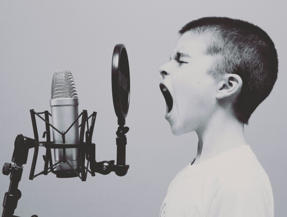 A young boy shouting into a microphone 